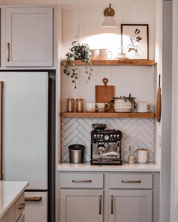 Light wood floating shelves coffee nook with herringbone tile backsplash and plants diy coffee bar ideas from @tentrailshomestyling.