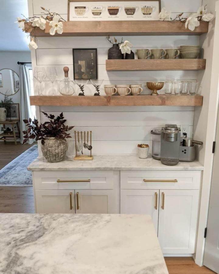 Natural wood floating shelves with white shiplap wall and marble countertop coffee nook by @realtorsardella bright and inviting beverage station.