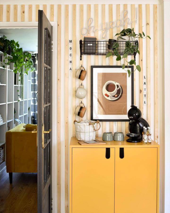 Bright yellow cabinet coffee nook with wood paneling wire basket and hanging mugs from @grillodesigns cozy and colorful beverage station