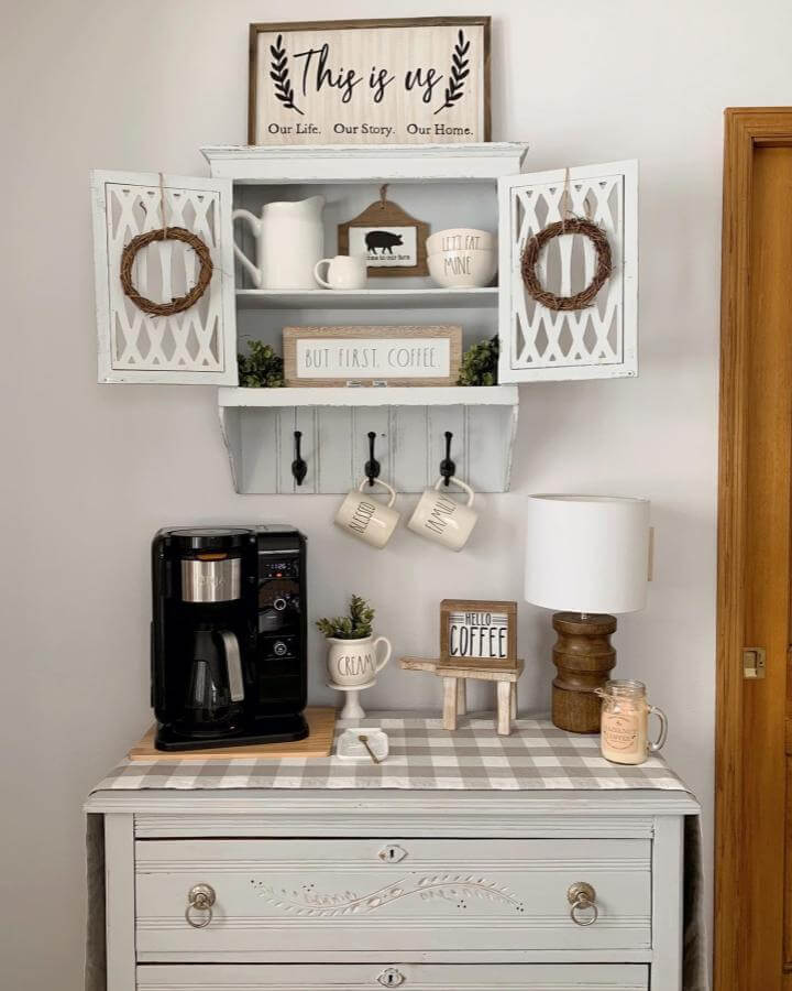 White distressed vintage cabinet coffee bar with gingham tabletop from @our.grace.filled.home showing farmhouse mugs and decor accents.