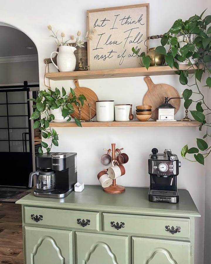 Soft green vintage cabinet coffee station with wooden shelves and plants by @greeneacreshome cozy and rustic beverage corner.