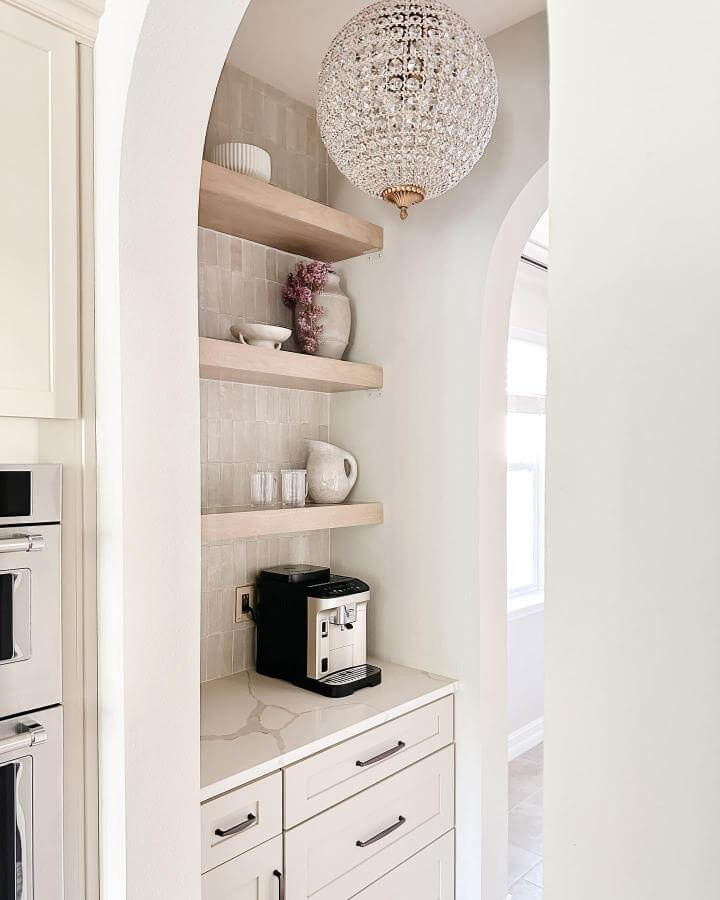Light neutral kitchen coffee nook with floating wood shelves and soft tile backsplash from @apieceofmyhaven. Cozy minimalist coffee station with natural elements and clean lines.