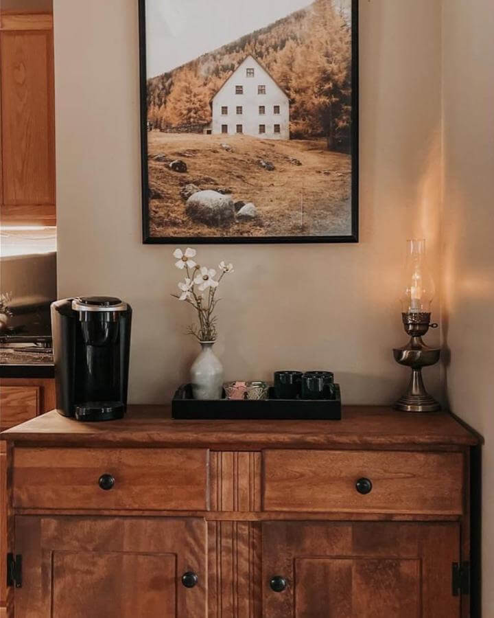Warm wooden coffee bar with black accents and vintage lamp from @crows.hollow. Rustic, cozy corner with simple decor and functional setup.