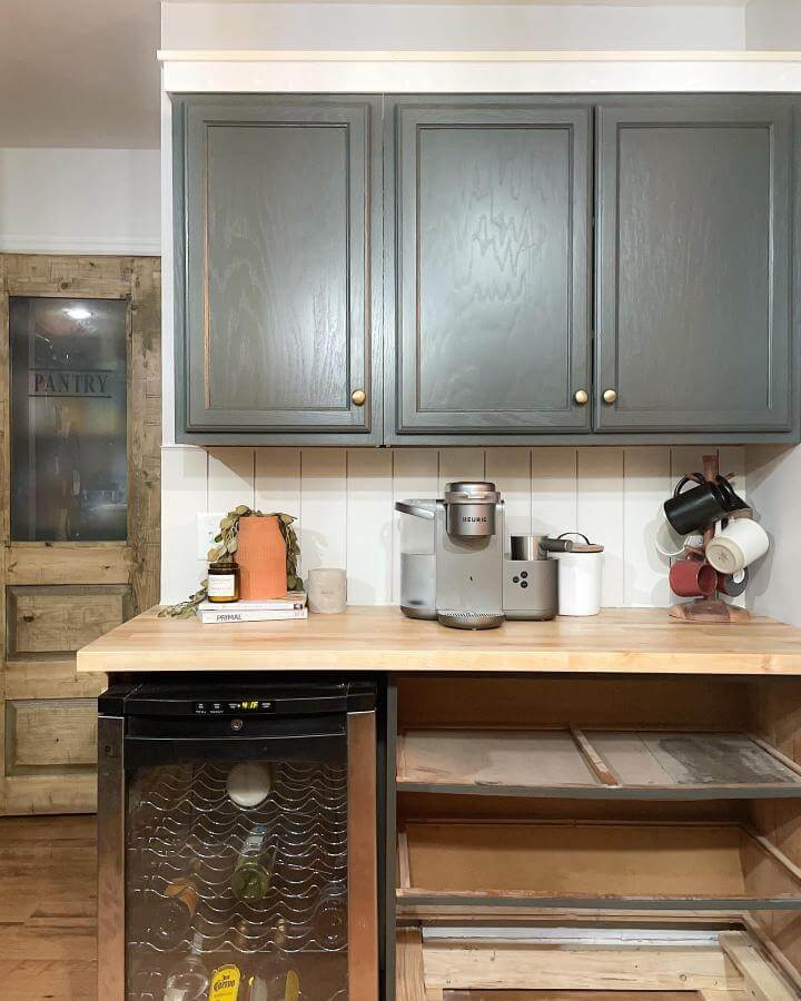Gray rustic kitchen coffee station with wooden countertop and brass knobs from @diy.ourhome. Cozy, functional home coffee setup with storage and style.