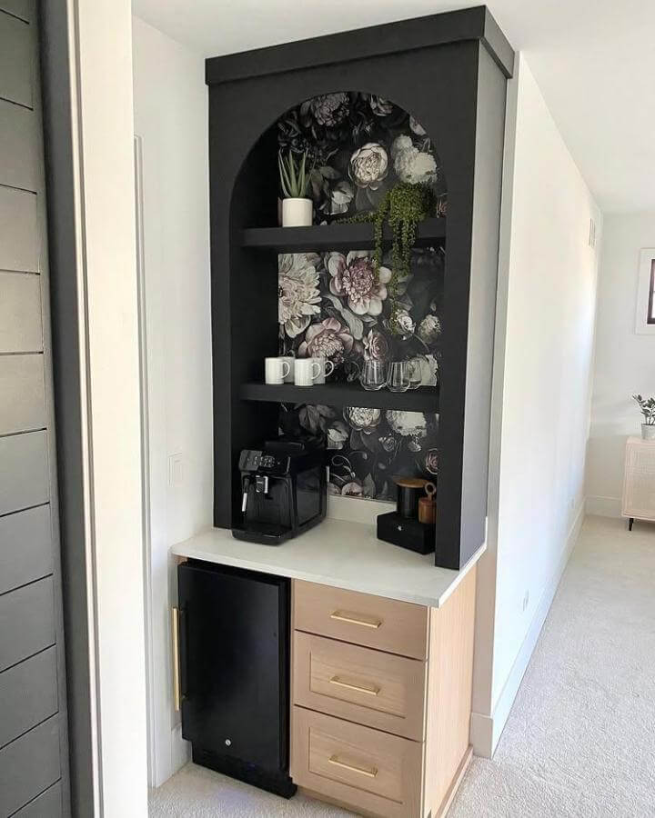 Black arched alcove with floral wallpaper and wooden cabinetry creates chic diy coffee bar ideas by @laurenelizabethburke with cozy shelves and greenery.