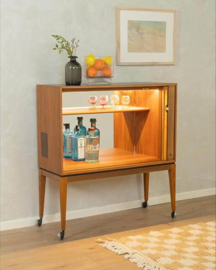 Mid century wooden upcycled Grundig TV cabinet turned drinks cabinet with glassware and bottles on display