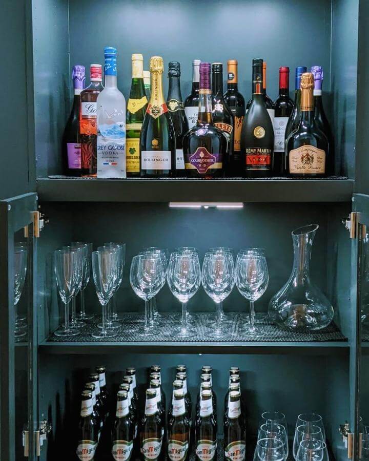 Dark teal painted IKEA BILLY bookcase DIY drinks cabinet ideas with glassware and bottles by @livin_on_a_crescent. Stylish and organized home bar.