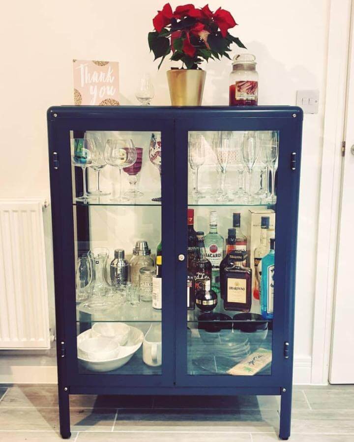 Blue IKEA FABRIKÖR cabinet used as drinks cabinet by @pintsizecaz with glass shelves and clear doors showcasing glassware and bottles.