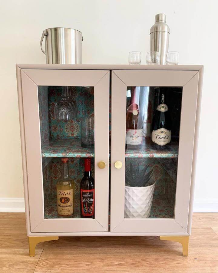Blush pink cabinet with brass accents and patterned blue-red interior from @restore_refurbish_revive showcasing diy drinks cabinet ideas.