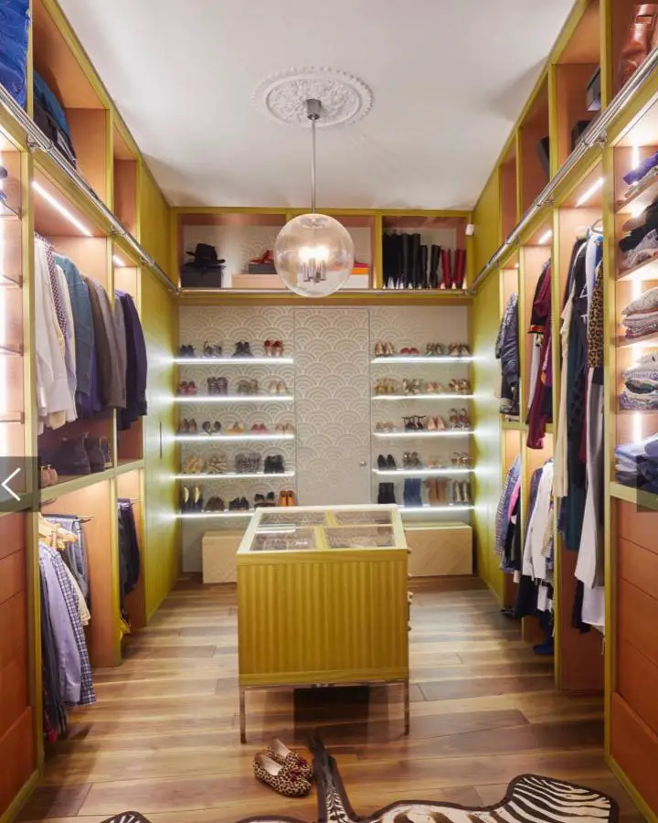Mustard yellow walk-in closet from @emmastevensonstudio with illuminated shoe displays and center island.