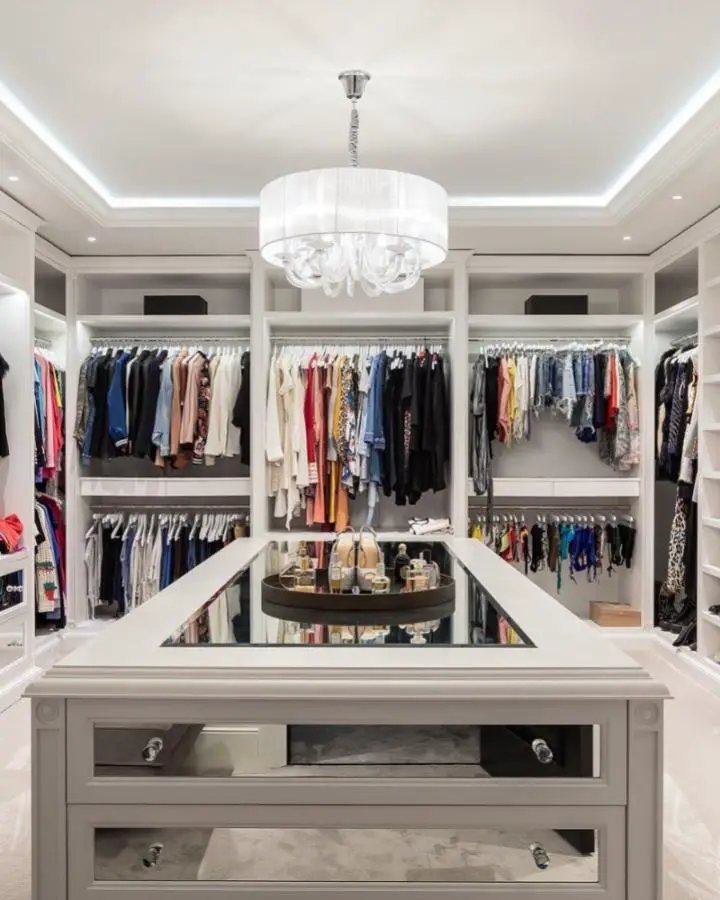 White drum chandelier with crystals from @sgsdesigninteriors. Luxury lighting centerpiece in organized walk-in closet space.