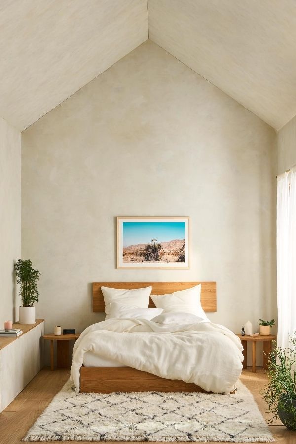 Tranquil bedroom featuring a vaulted ceiling, soft hues, and sunlight.