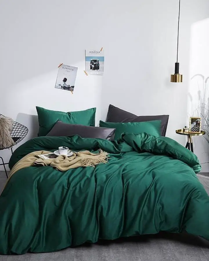 Luxurious emerald bedding set from @modernspaceliving with charcoal accent pillows and brass pendant lighting.