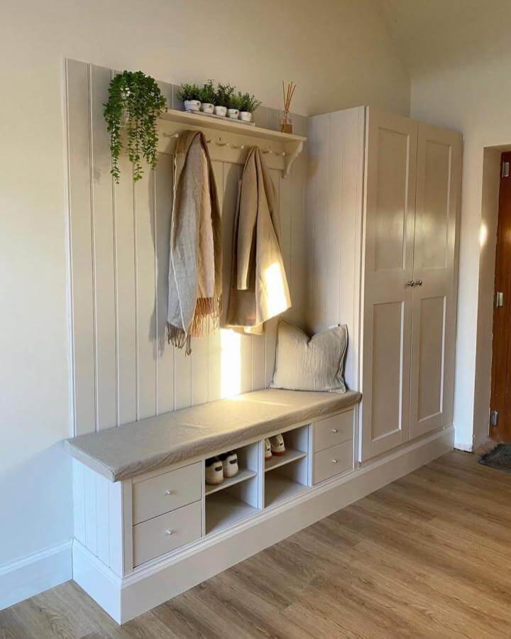 Cream colored built-in bench with IKEA PAX and KALLAX units for entryway shoe storage ideas by @skyebarnconversion, bright cozy corner with hooks and cushions.