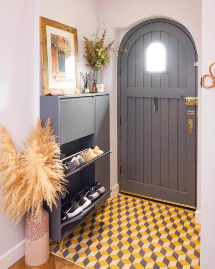 Dark gray modern shoe cabinet with brass feet in stylish entryway by @organisedbycharlotte showcasing tilt-out compartments and patterned tile floor.