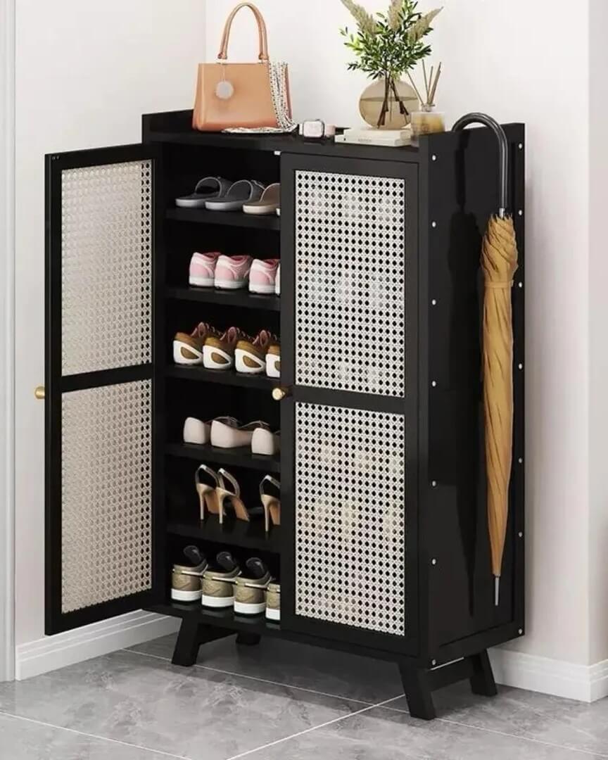 Black bamboo shoe cabinet with cane panel doors by @sk_collection789 featuring multiple shelves and umbrella storage in a bright entry nook.