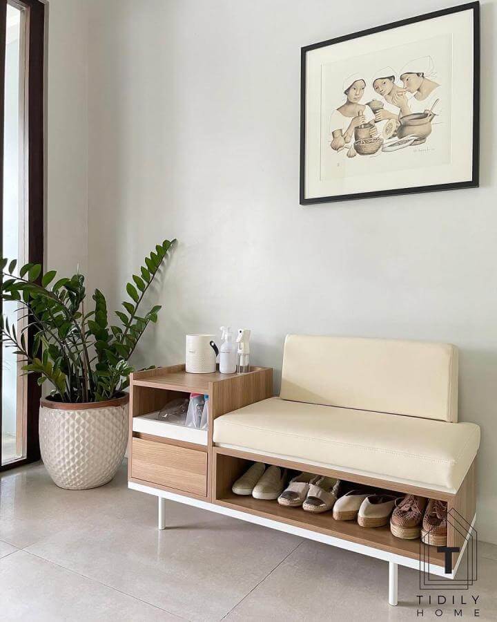 Cream cushioned bench with wooden open shelves and white metal frame in modern entryway for shoe organization.