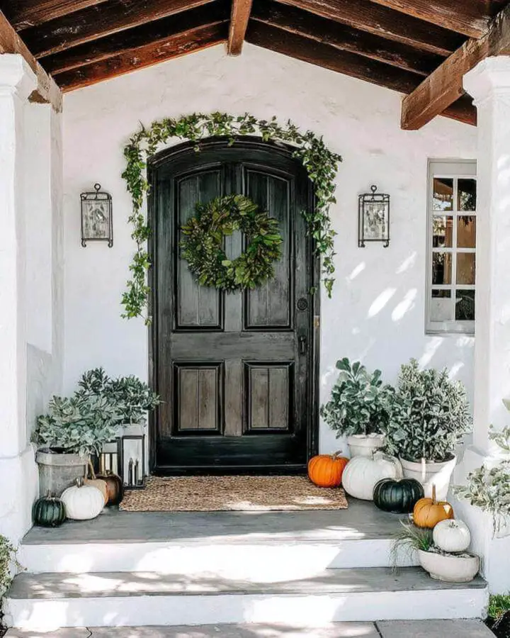 Rustic front door entrance with cascading ivy and autumn pumpkin display on white porch steps.
