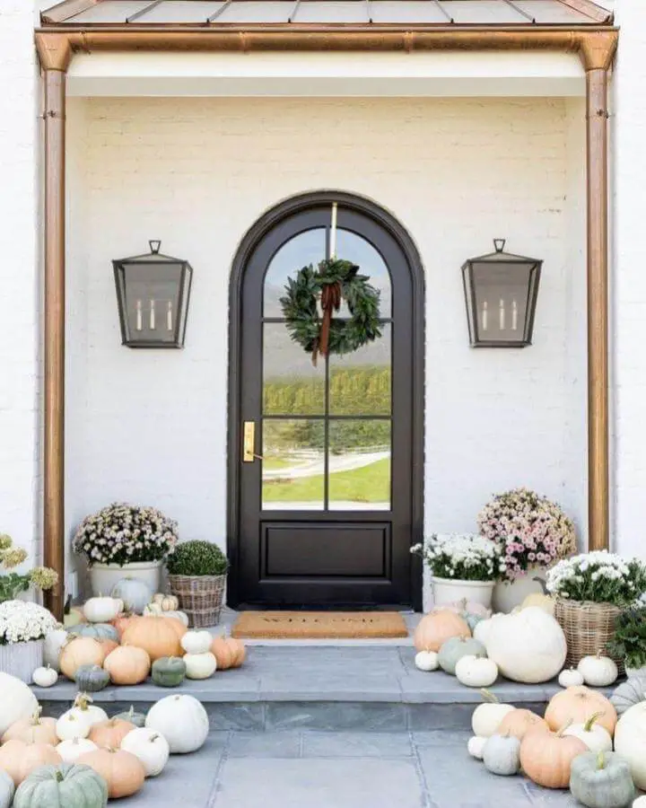 Elegant front entry with pastel pumpkins from @thegaikowskigroup. Soft autumn colors enhance welcoming doorway.