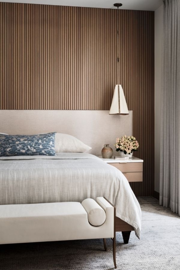 Modern bedroom featuring a wood fluted wall, sleek furnishings, cozy ambiance.