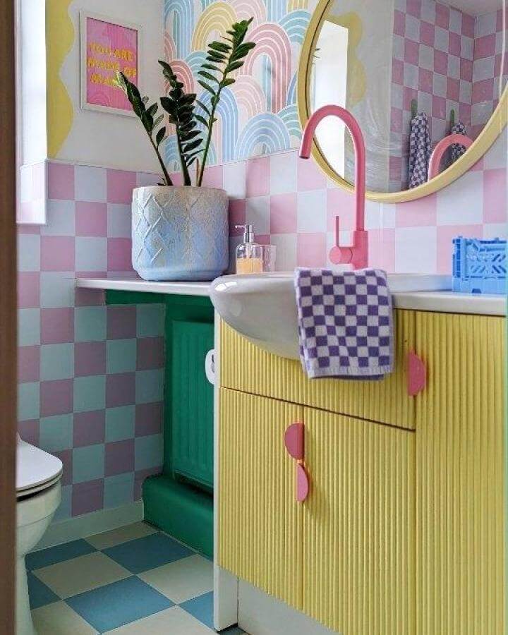 Colorful pastel bathroom with checkerboard tiles and ribbed yellow cabinetry from @the.mental.temple featuring playful funky bathroom ideas and pink accents