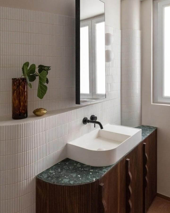 Green terrazzo countertop bathroom vanity with white basin and dark wood cabinets from @ext_design. Textured tiles and matte black fixtures create funky bathroom ideas ambiance.