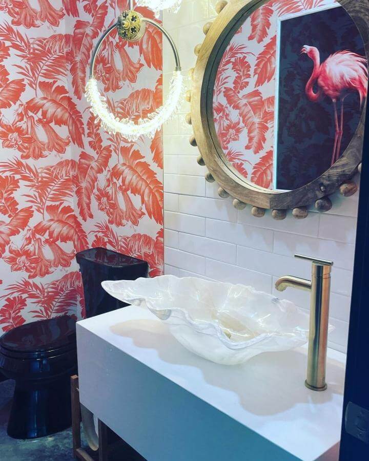 Coral tropical wallpaper and shell-shaped glass sink funky bathroom ideas from @emilychesnutdesign with brass fixtures and white subway tiles.