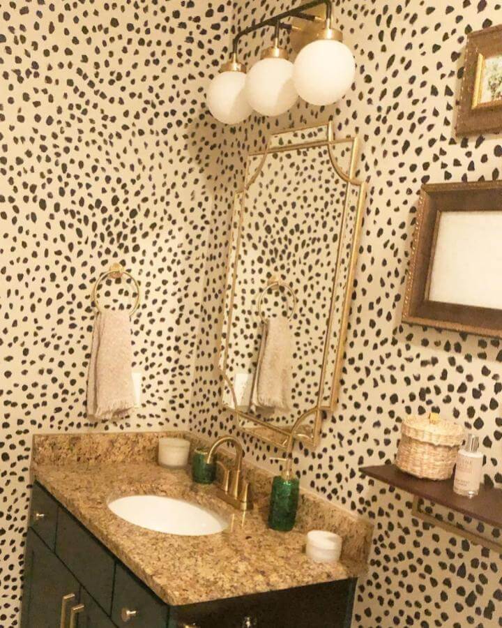 Creamy wallpaper with black spots bathroom wall and gold fixtures from @brittney.w.conroy funky bathroom ideas with granite countertop and classic accents