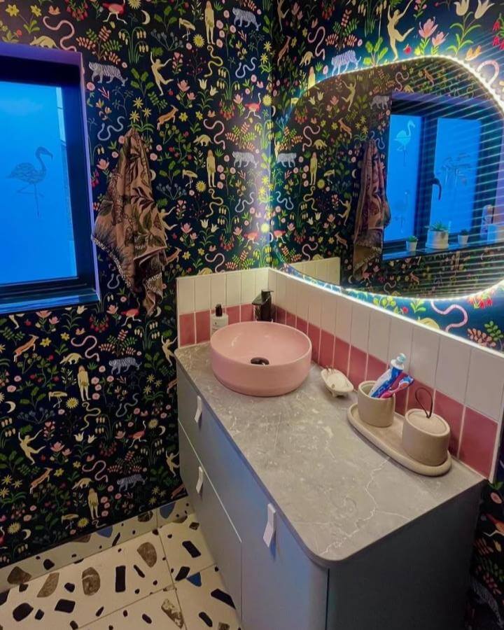 Dark blue jungle wallpaper bathroom with pink sink and terrazzo floor from @sophiaslittlecasa showcasing funky bathroom ideas.
