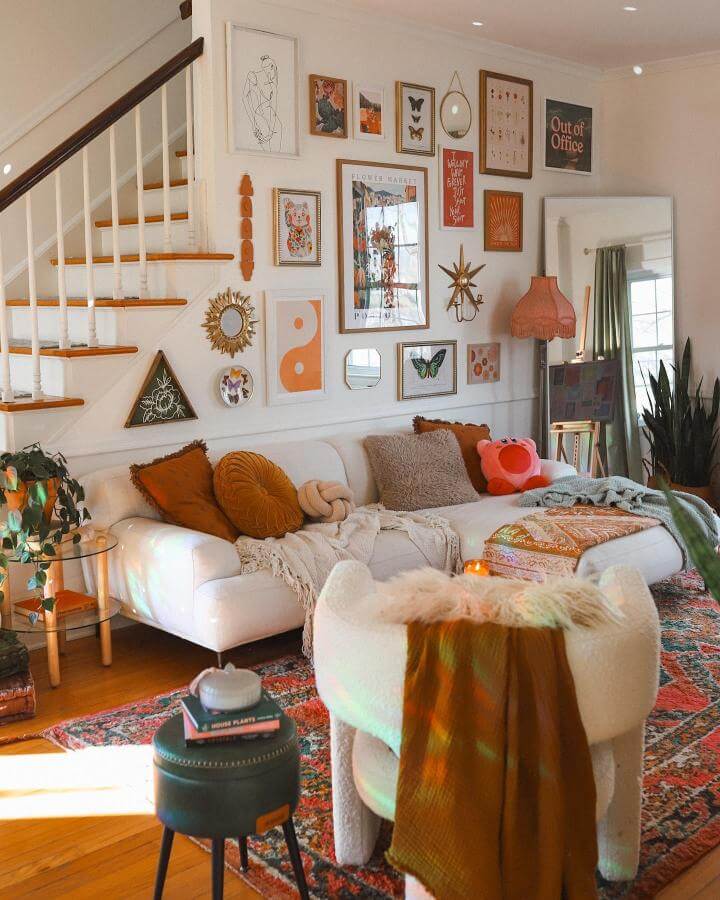 Warm burnt orange and beige mixed media living room wall display from @goldenhourabode showing art prints, mirrors, and decorative objects in a cozy home setting.