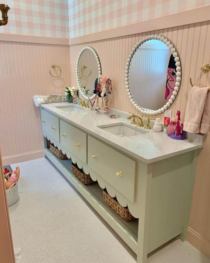 Soft pastel green scalloped vanity with gold fixtures and pink bead-framed mirrors in girly bathroom ideas by @lonestarvalleyfarm. Elegant, playful mix.