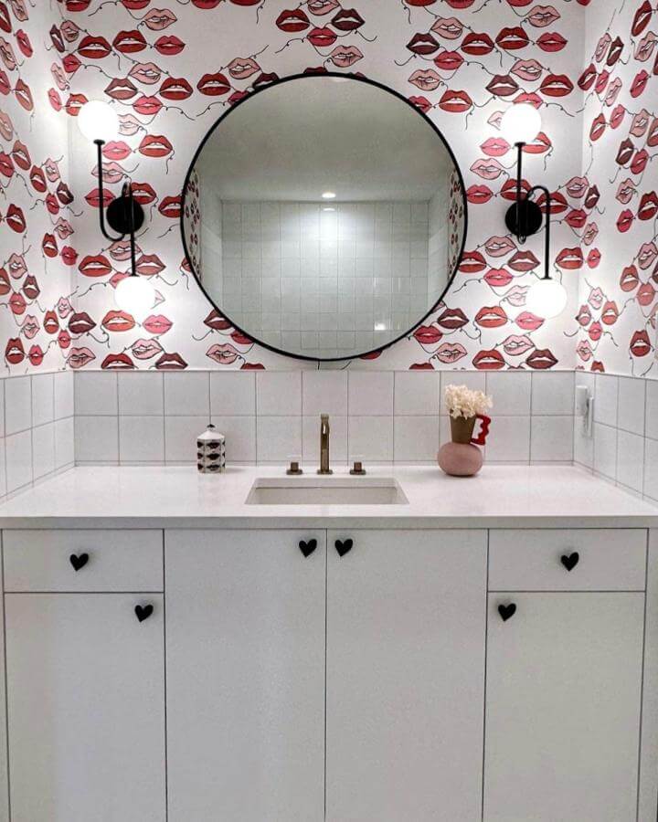 White tile bathroom with red and pink lips wallpaper and black heart knobs from @gableridge_wallcoverings girly bathroom ideas playful and chic design.