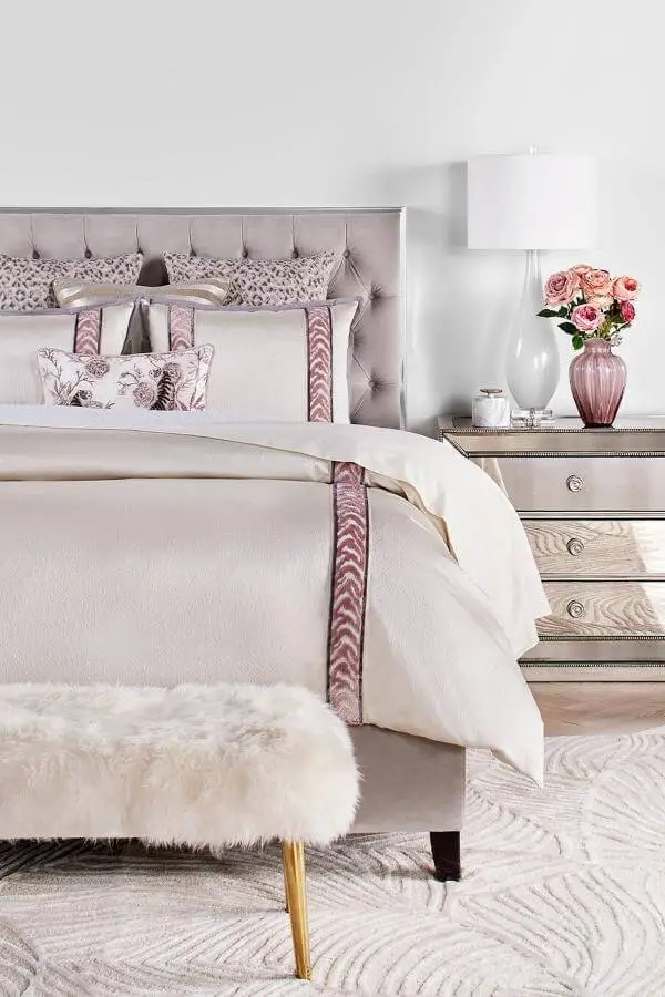 Tufted gray headboard with mauve-trimmed bedding from @zgallerie. Mirrored nightstand and pink roses complete the look.