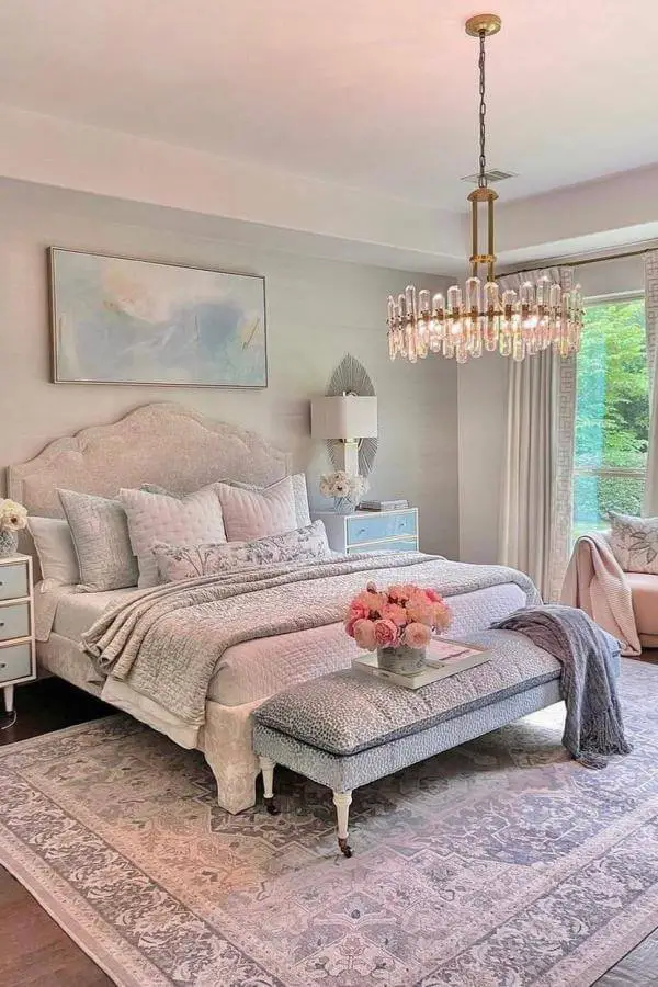 Luxurious bedroom with crystal chandelier from @decorgold. Blush pink bedding and elegant brass lighting fixture.