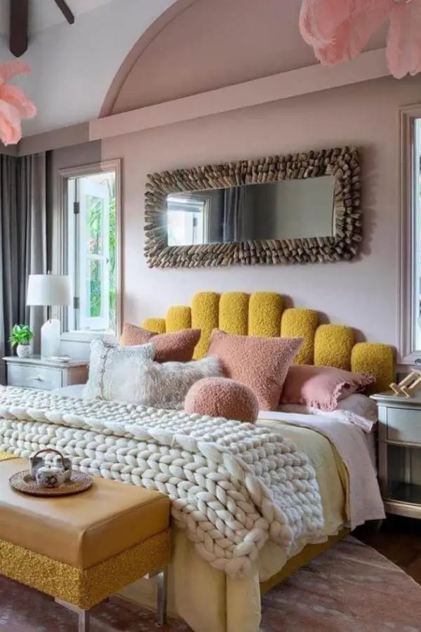 Cream chunky knit throw blanket from @lamaisonpierrefrey layered over mustard yellow upholstered headboard with pink accents.