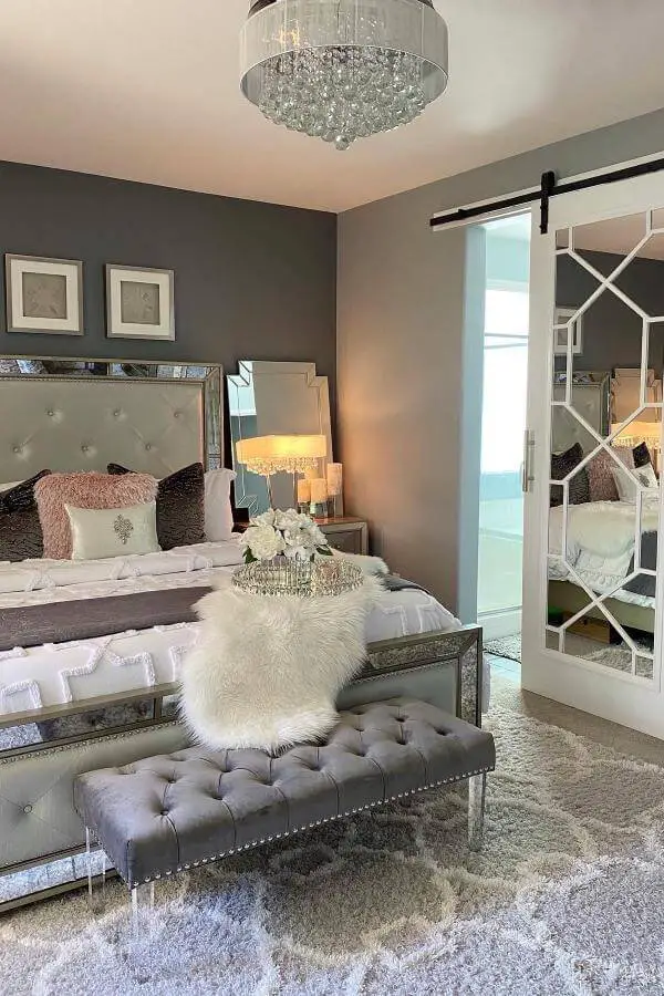 Crystal chandelier bedroom from @designsbyjeana. Mirrored furniture and gray walls create luxurious atmosphere.