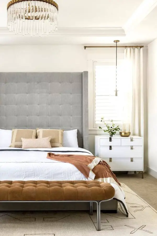 Cognac leather tufted bench from @ninajizhar. Features button detailing and chrome legs in neutral bedroom.