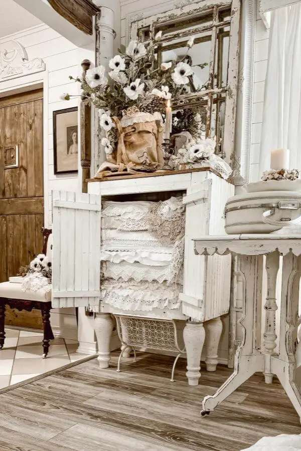 Distressed white cabinet from @thegeorgianwhitepoppy displaying layered vintage lace textiles and cotton stems