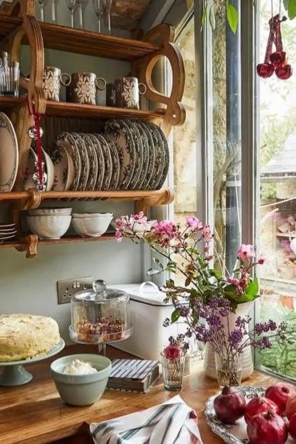 Rustic wooden plate rack from @h0neybeecottage displaying vintage dishes with fresh flowers and cottage kitchen styling.