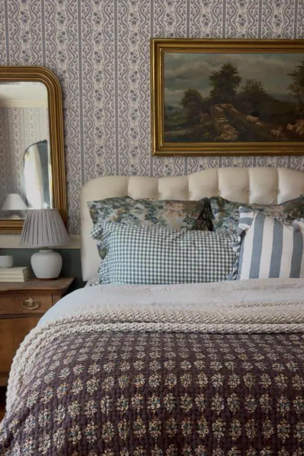 Traditional bedroom with mixed textile patterns from @ruefer.heartandhome. Geometric wallpaper anchors layered bedding in muted tones.
