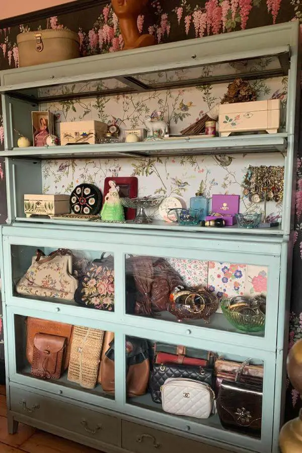 Weathered mint cabinet from @somethinginthehills displaying vintage purses, ceramics, and nostalgic collectibles behind glass doors.