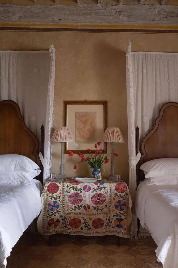 Embroidered textile chest from @louiseroehome. Twin beds with vintage suzani nightstand and exposed ceiling beams.