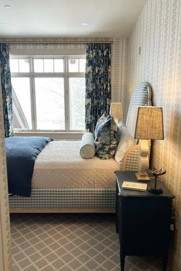 Navy floral curtains and gingham bedding from @torirubinsoninteriors. Cozy traditional bedroom with pattern mixing and vintage charm.