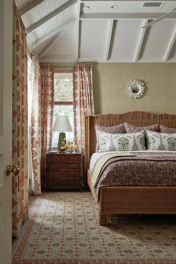 Wicker rattan bed frame from @torirubinsoninteriors. Features vertical slats with floral bedding and cottage styling.