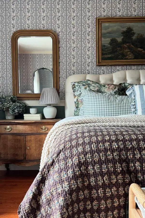Ornate bronze mirror from @ruefer.heartandhome. Features curved edges and detailed metalwork above floral bedding.