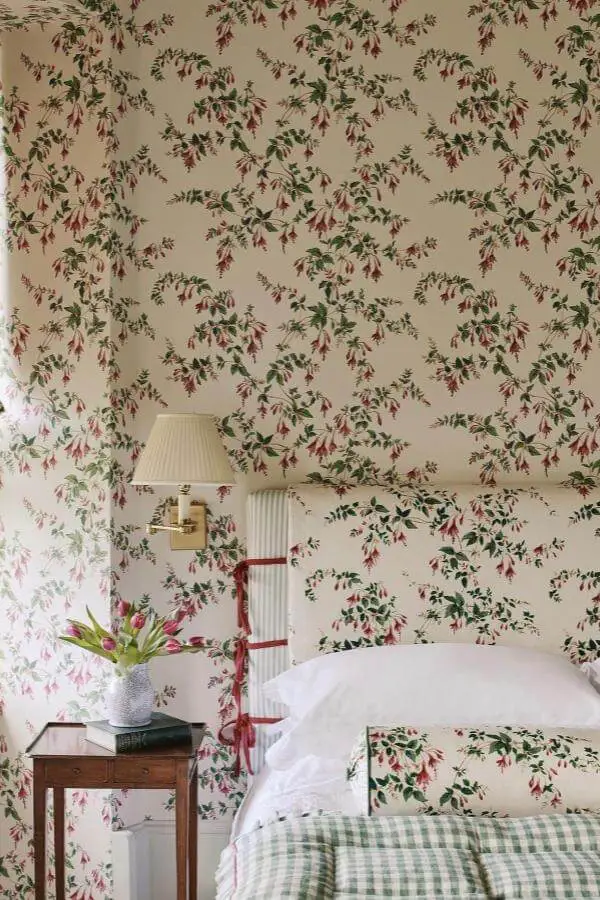 Floral wallpaper bedroom from @alyce.taylor.studio. Botanical pattern covers walls and bedding with vintage brass sconce.