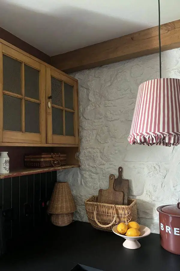 Rustic kitchen corner from @bealach_uige_bothy featuring red striped pendant light and stone walls.
