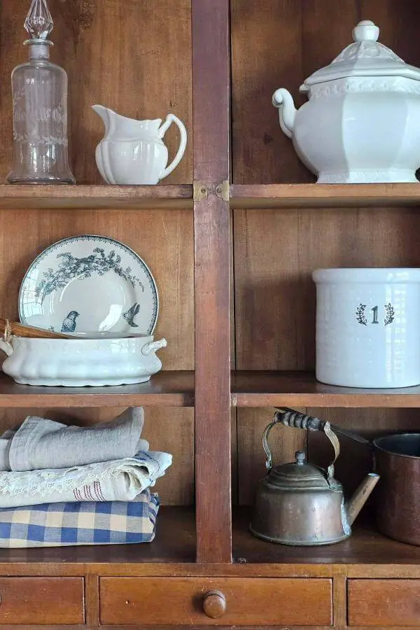 Vintage white ironstone display from @farmhousewares. Mixed with blue transferware and copper kettle on wooden shelves.