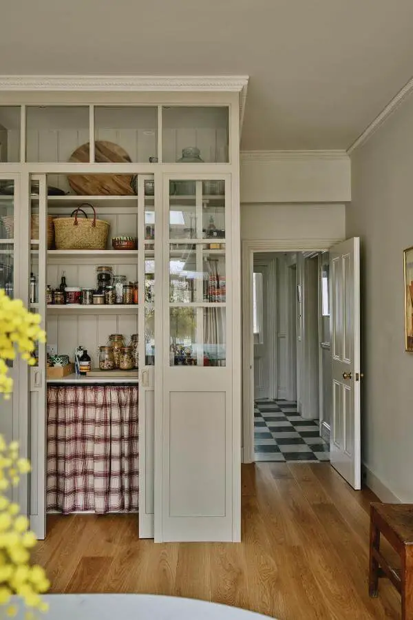 Cream glass-front pantry cupboards from @emma__ainscough featuring grandmacore kitchen ideas with gingham curtain details and vintage storage displays.
