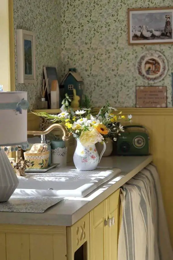 Cream kitchen cabinetry from @cooneynest. Vintage floral wallpaper and fresh flowers complete the cozy traditional styling.